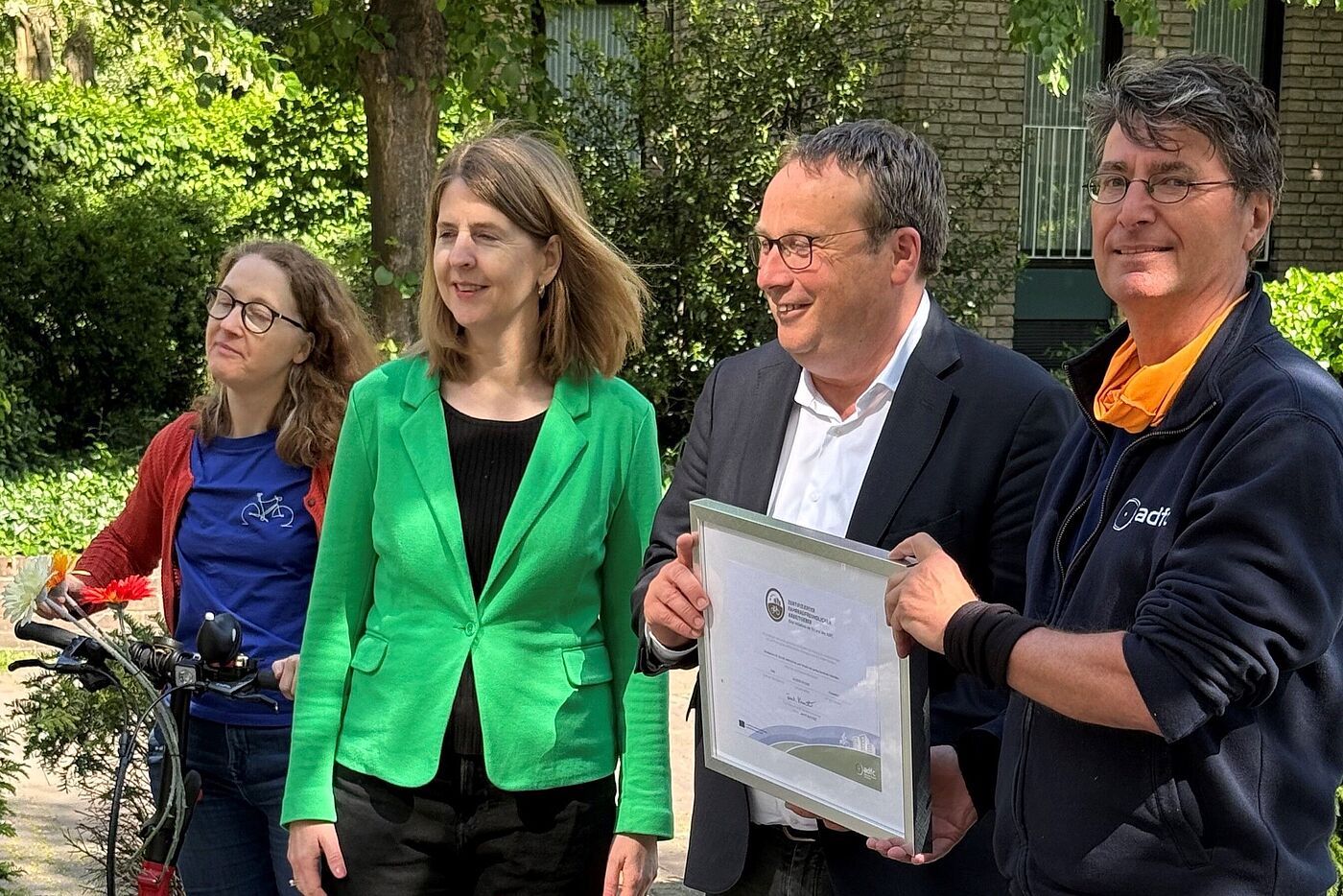 Zertifikatsübergabe MUNV (Re-Zertifizierung) Minister Krischer (2. v. r.) hält das Zertifikat für das Ministerium für Umwelt, Natur und Verkehr (MUNV) des Landes Nordrhein-Westfalen in der Hand. Die Übergabe für die Re-Zertifizierung erfolgte am 6. Mai 2025. v. l. n. r. Susanne Niemann (Landesvorsitzende ADFC NRW), Dr. Sandra Terporten (Referatsleiterin „Rad- und Fußverkehr, Verkehrssicherheit“, MUNV), Oliver Krischer (Minister MUNV), Dr. Andreas K. Bittner (Auditor, ADFC NRW)