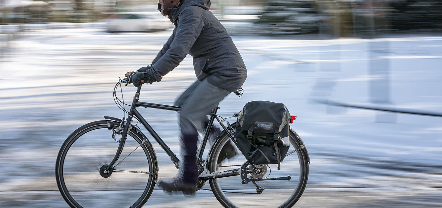 Ein Radfahrer im Winter Ein Radfahrer auf einer winterlichen Straße mit Schnee.